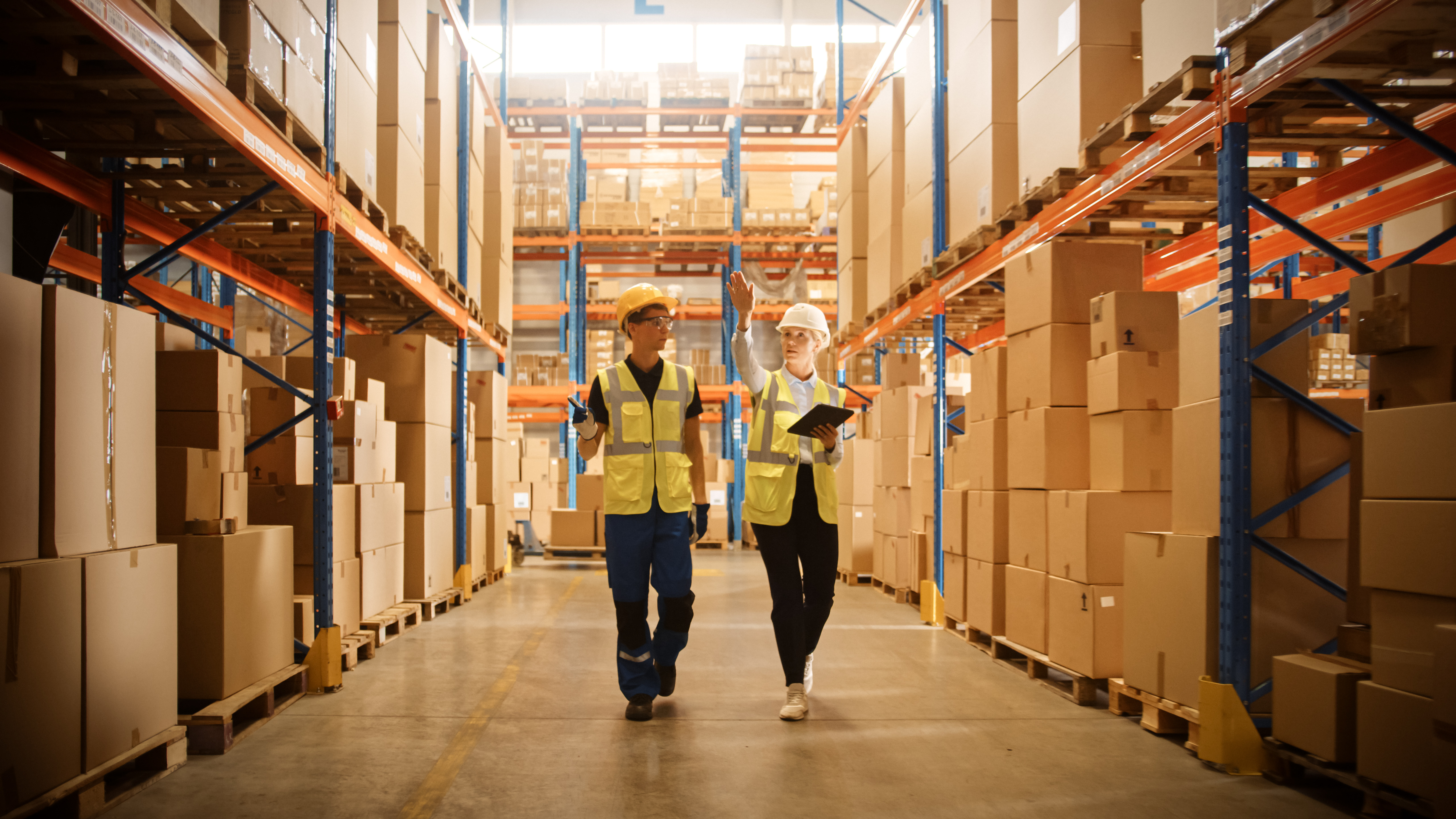 ChatGPT said:  Mannelijke werknemer en vrouwelijke supervisor gebruiken een digitale tablet om de magazijnindeling te bekijken en de warehouse space optimization in een retailmagazijn te verbeteren.